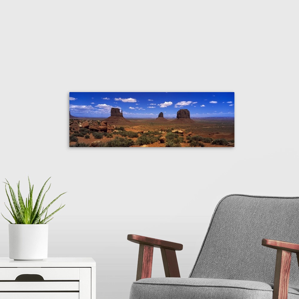 A modern room featuring Panoramic photo on canvas of three tall rock formations in the desert under a bright blue sky.