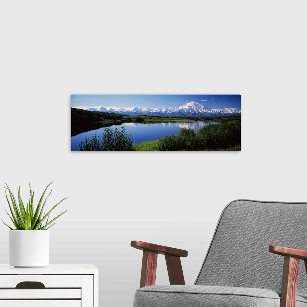 A modern room featuring Panoramic photograph of snow covered mountains under a clear sky with rolling grass hills and riv...