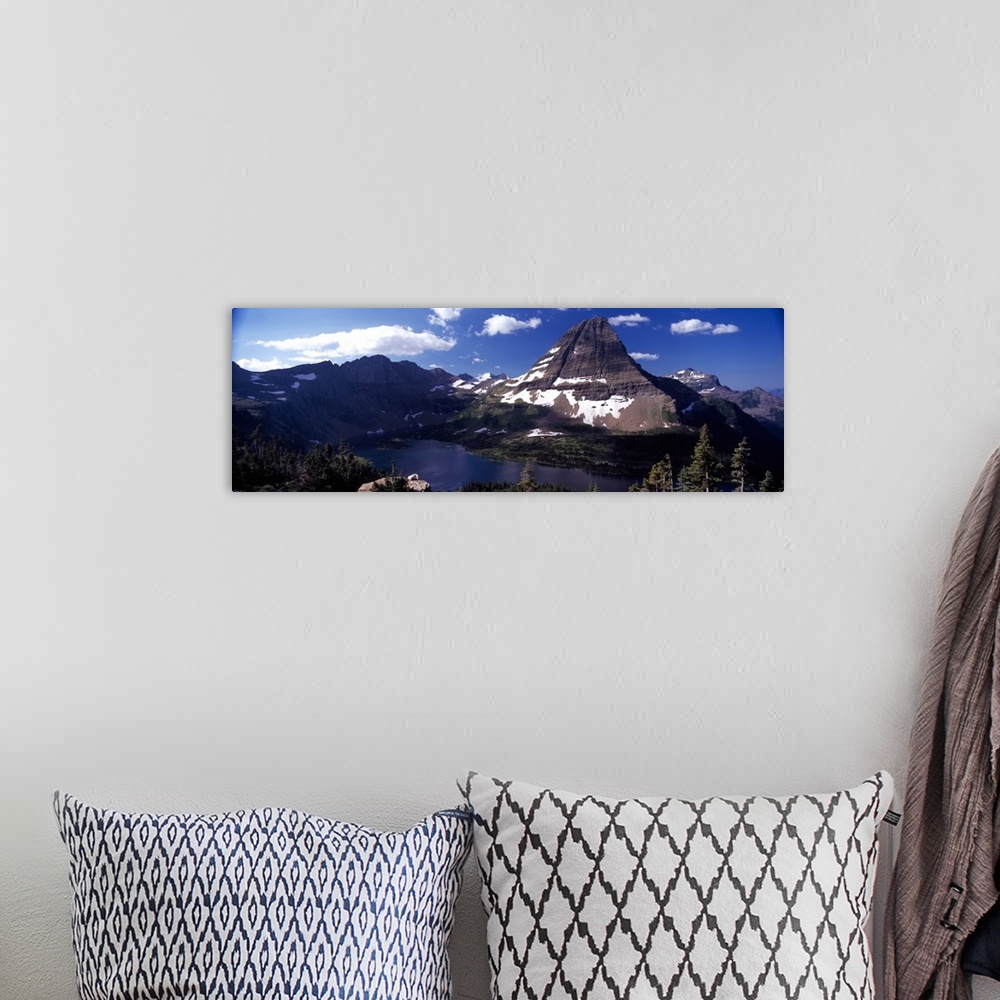 A bohemian room featuring An immense mountain in front of a large lake is photographed in wide angle view.