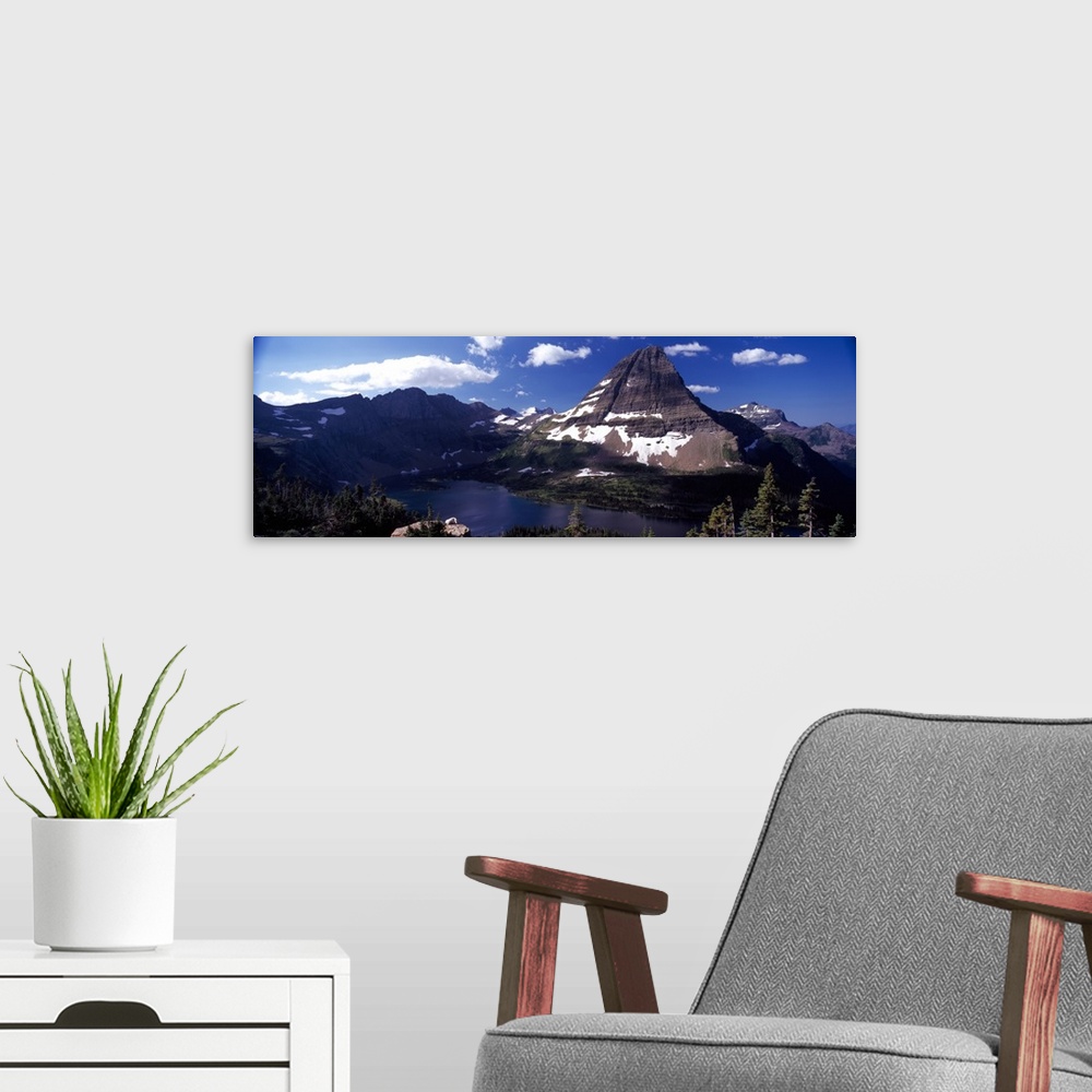 A modern room featuring An immense mountain in front of a large lake is photographed in wide angle view.