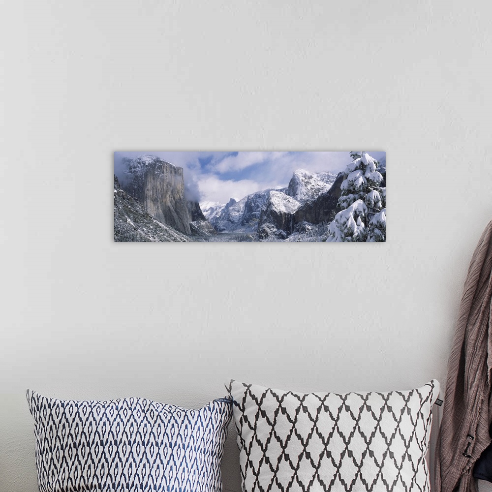 A bohemian room featuring This panoramic photograph is taken of immense mountains that reach up into the clouds and are cov...