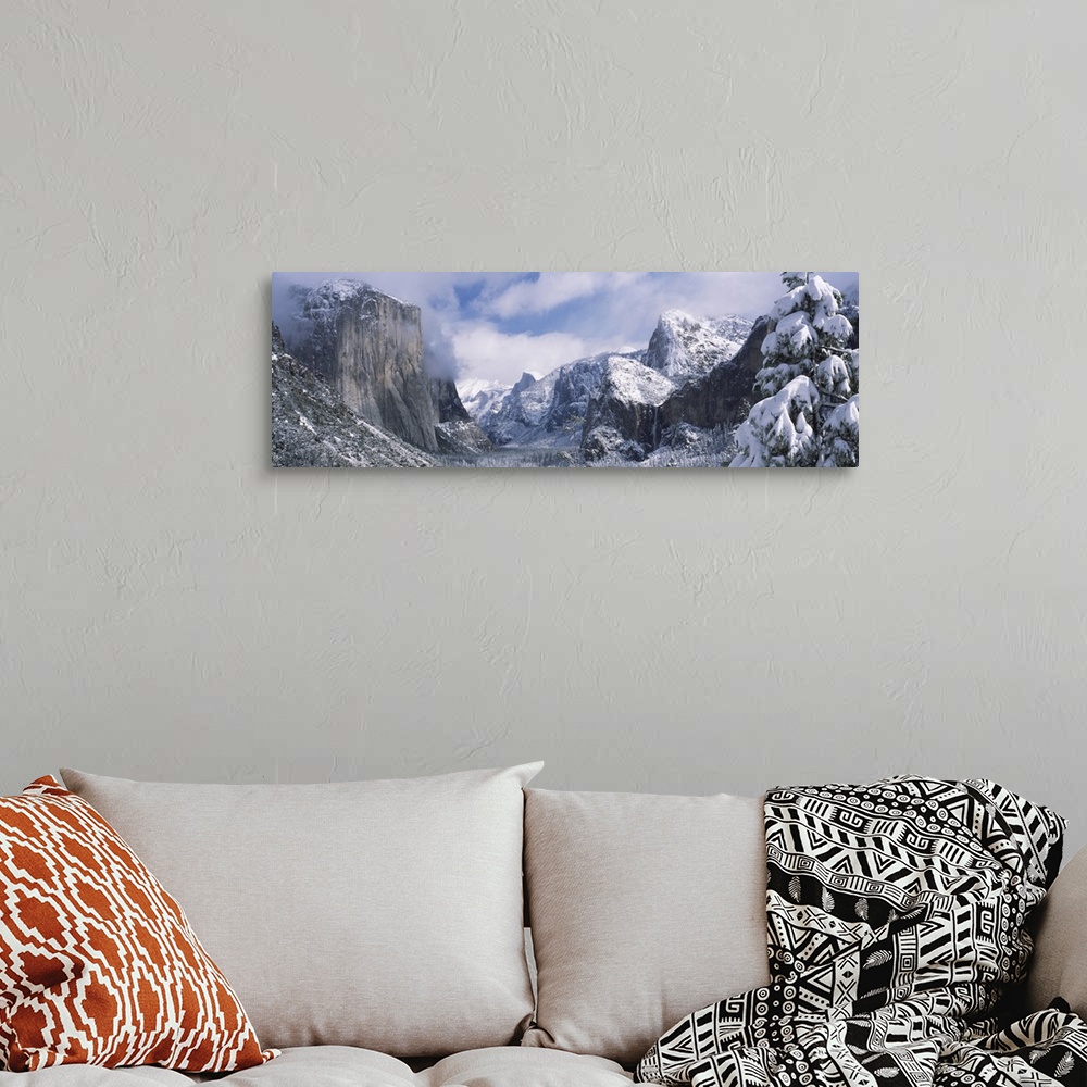 A bohemian room featuring This panoramic photograph is taken of immense mountains that reach up into the clouds and are cov...
