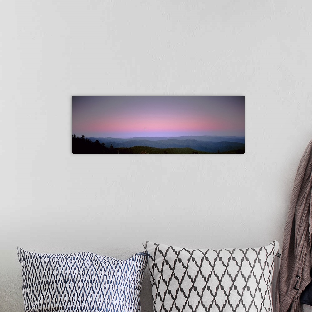 A bohemian room featuring Mountains in the distance are photographed under a sunset sky with a small view of the moon.