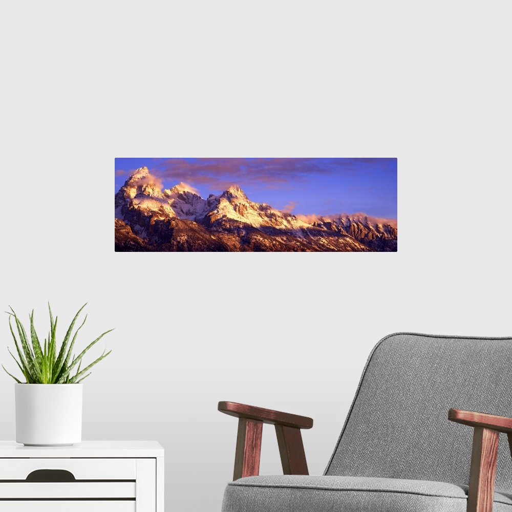 A modern room featuring Panoramic photograph of snow capped mountain range under a cloudy sky.