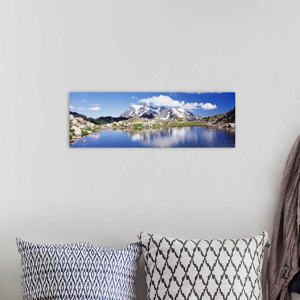 A bohemian room featuring An immense snow covered mountain is pictured in the background from across a large body of water ...