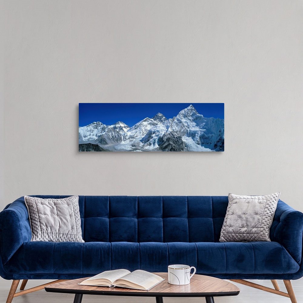 A modern room featuring Giant, wide angle landscape photograph of snow covered Himalaya Mountains against a blue sky, inc...