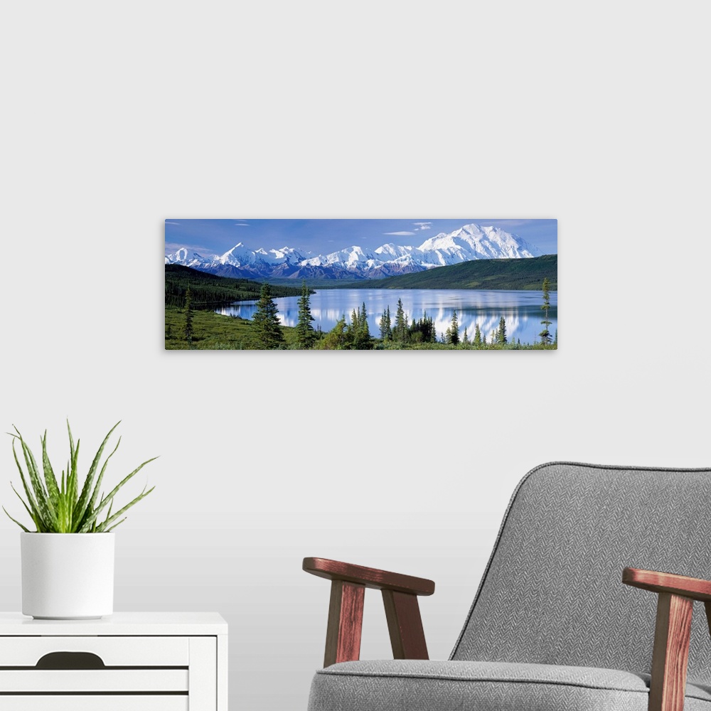 A modern room featuring Panoramic photograph shows a landscape filled with trees as they surround and reflect into a lake...