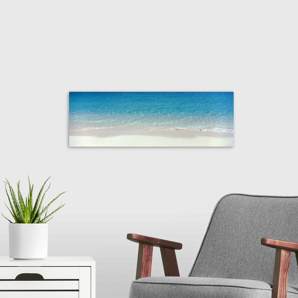 A modern room featuring Panoramic photograph of shoreline with wet sand and crystal clear water.
