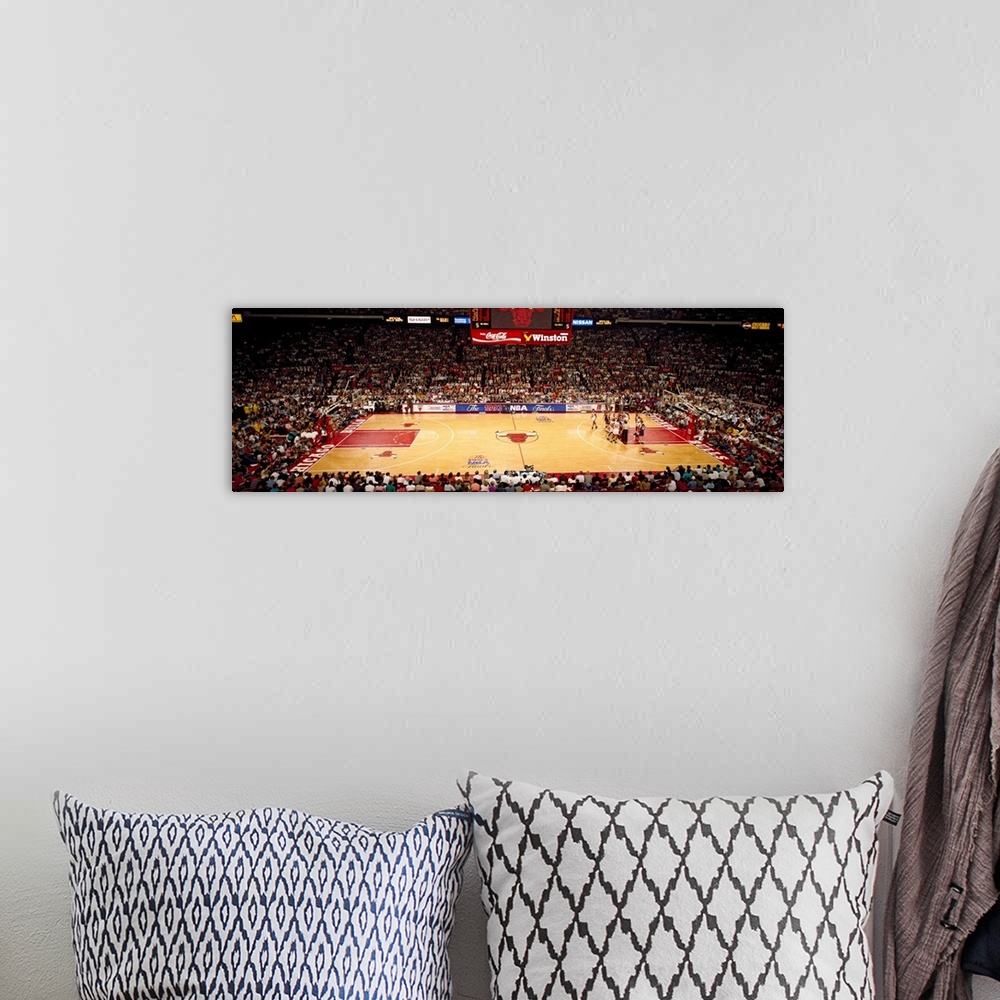 A bohemian room featuring This is a panoramic photograph of an arena and basketball game.