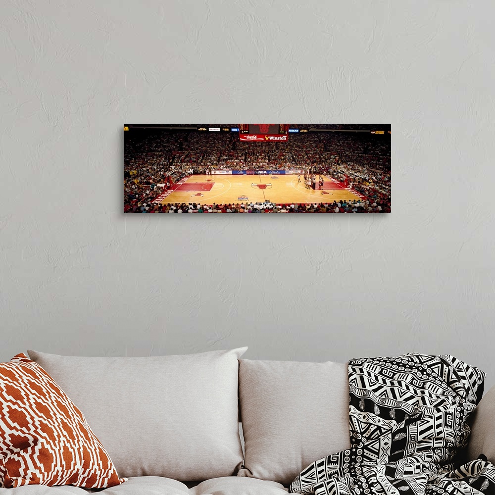 A bohemian room featuring This is a panoramic photograph of an arena and basketball game.