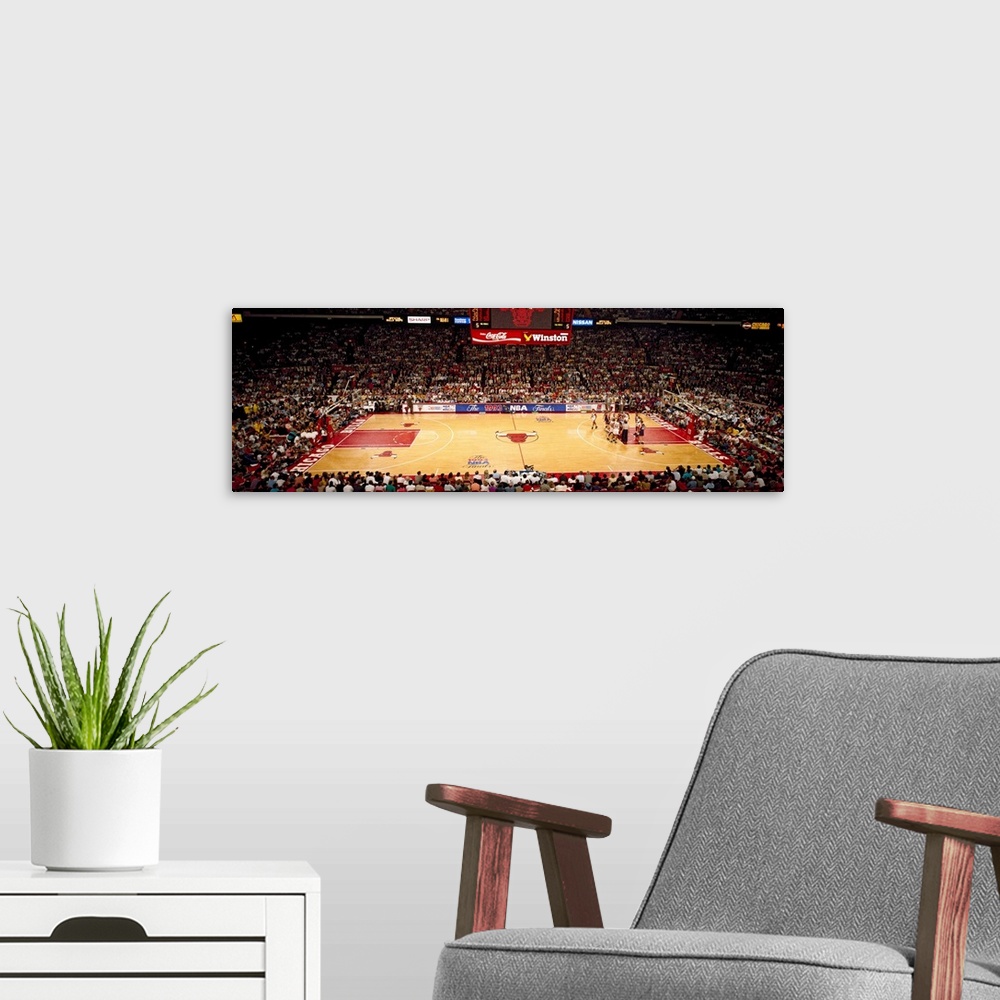 A modern room featuring This is a panoramic photograph of an arena and basketball game.