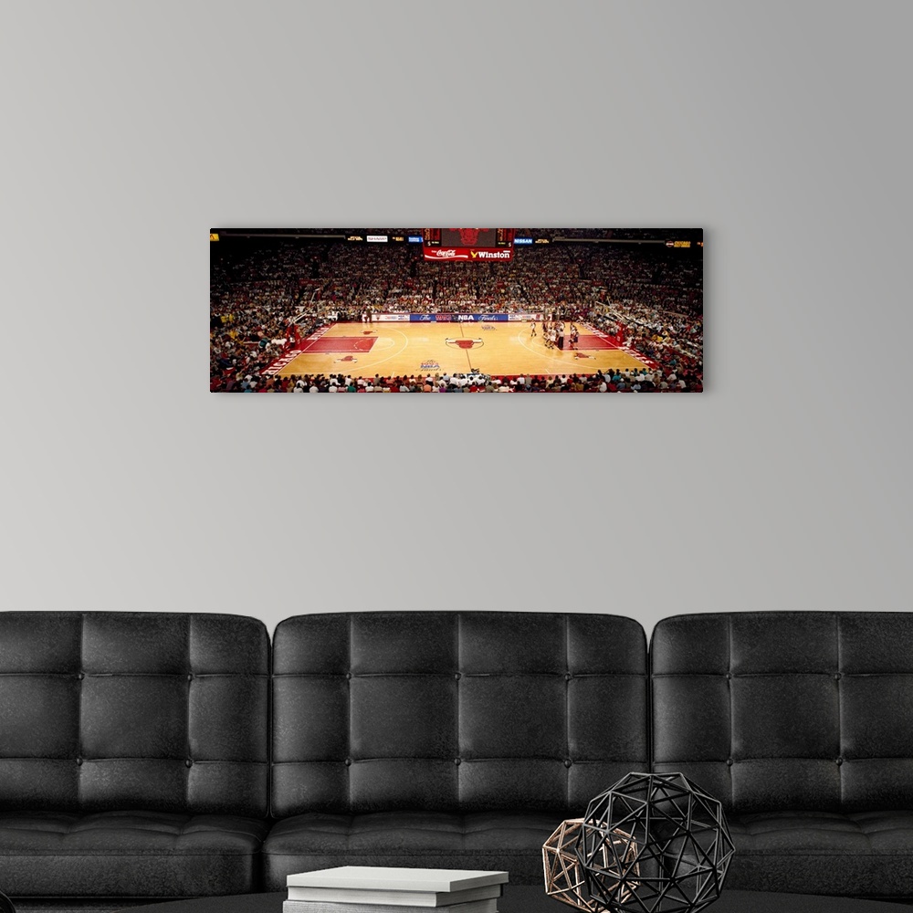 A modern room featuring This is a panoramic photograph of an arena and basketball game.