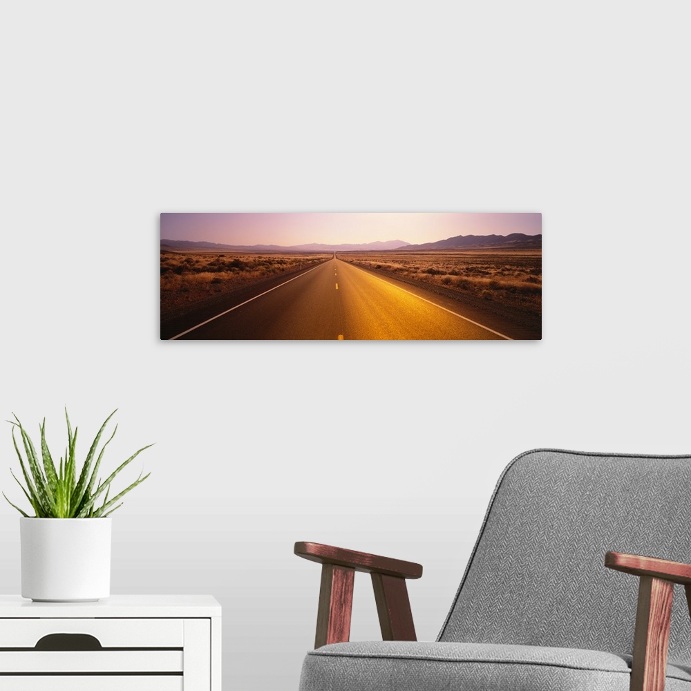 A modern room featuring Long horizontal canvas photo of a long two lane road going straight into the distance of a desert...
