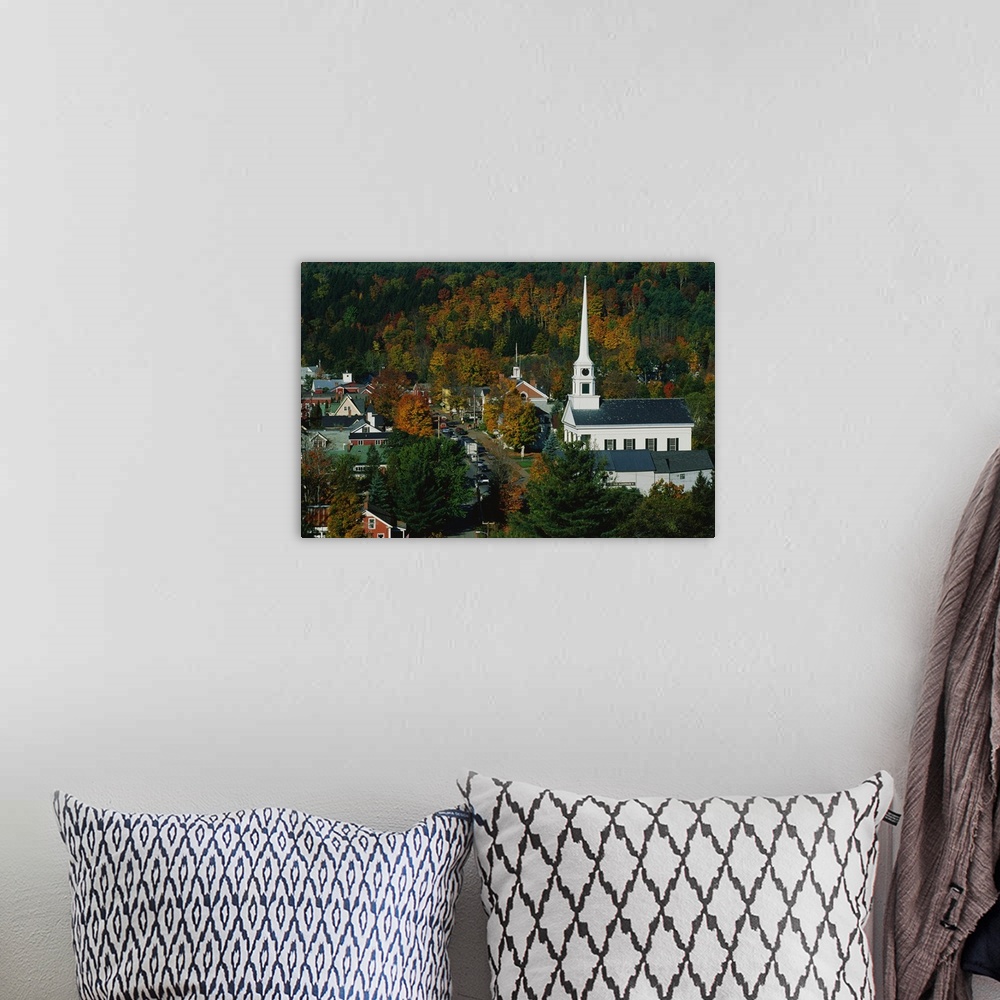 A bohemian room featuring Large photo of fall foliage surrounding a small town in Vermont with an old Church on the right.