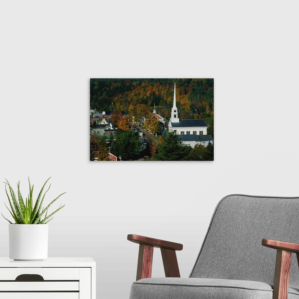 A modern room featuring Large photo of fall foliage surrounding a small town in Vermont with an old Church on the right.