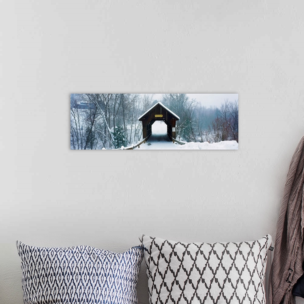 A bohemian room featuring A panoramic photograph of a one lane road through a covered bridge in a winter snowscape.