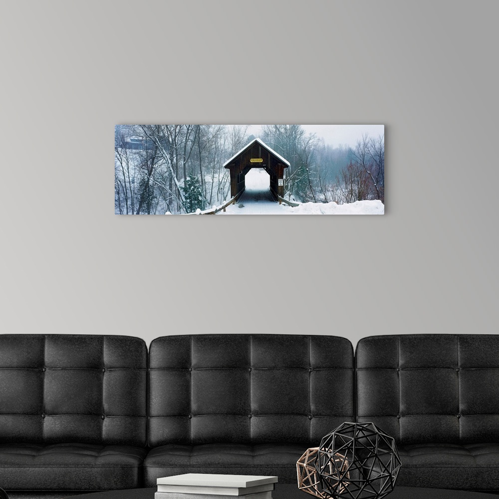 A modern room featuring A panoramic photograph of a one lane road through a covered bridge in a winter snowscape.