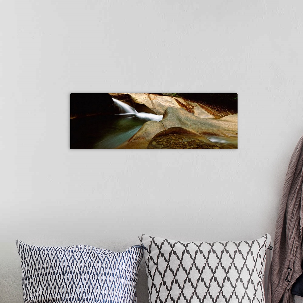 A bohemian room featuring Horizontal panoramic canvas of water traveling through rocky structures in a cave.