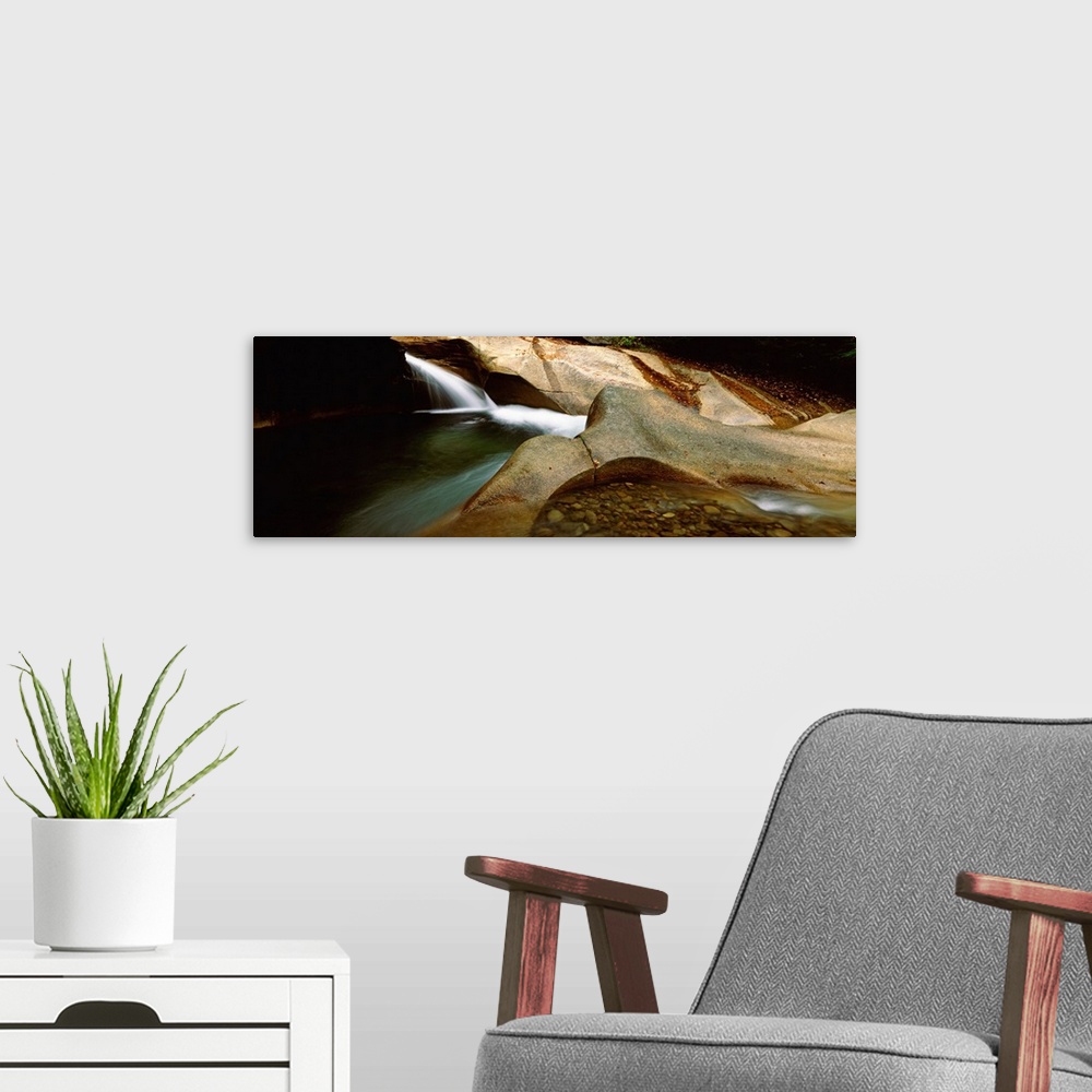 A modern room featuring Horizontal panoramic canvas of water traveling through rocky structures in a cave.