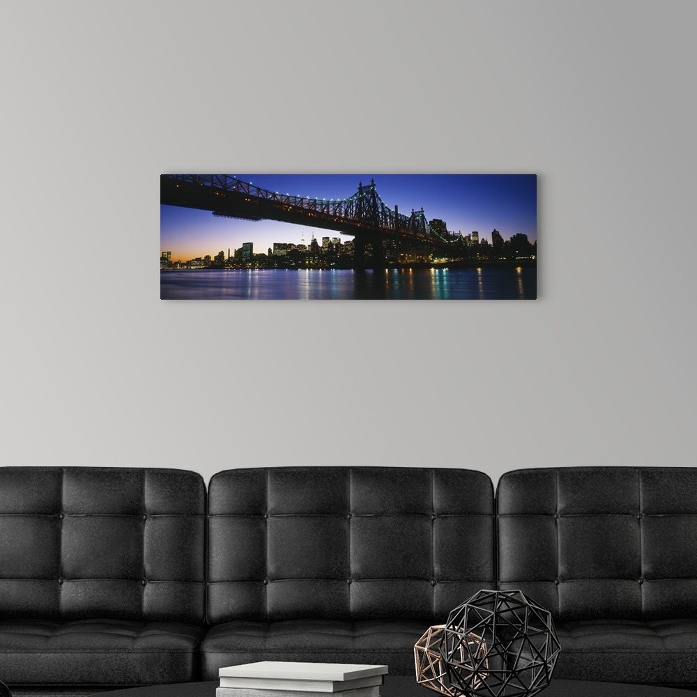 A modern room featuring Big, panoramic photograph of the 59th Street Bridge, lit at night, the New York City skyline in t...