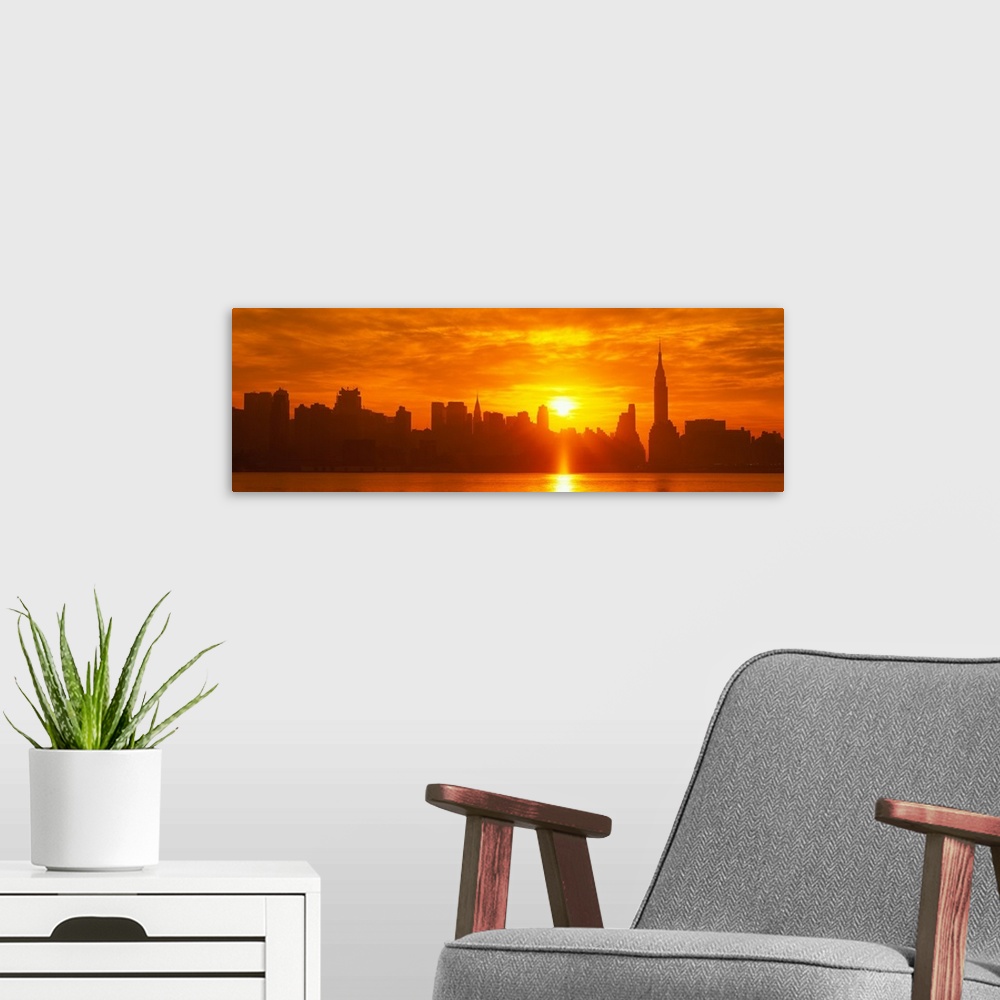 A modern room featuring This panoramic photograph shows the sun rising over Manhattan and making silhouettes of the city ...