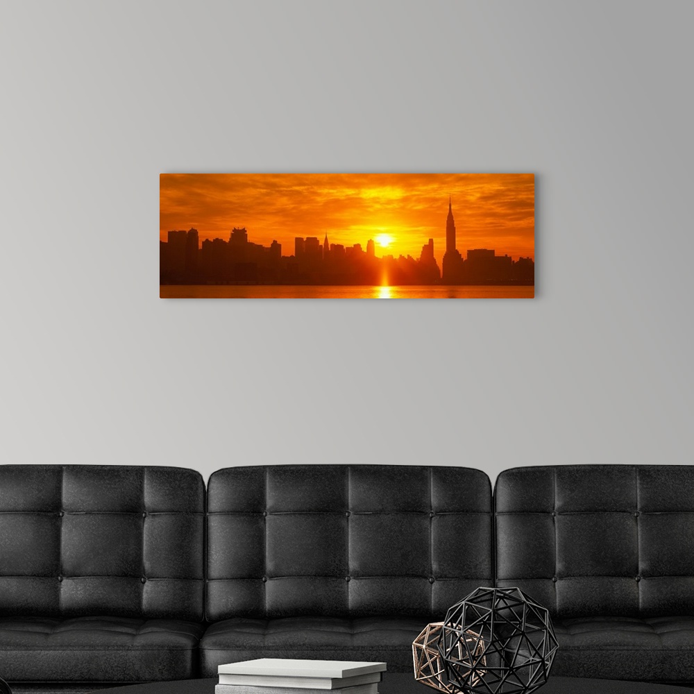A modern room featuring This panoramic photograph shows the sun rising over Manhattan and making silhouettes of the city ...