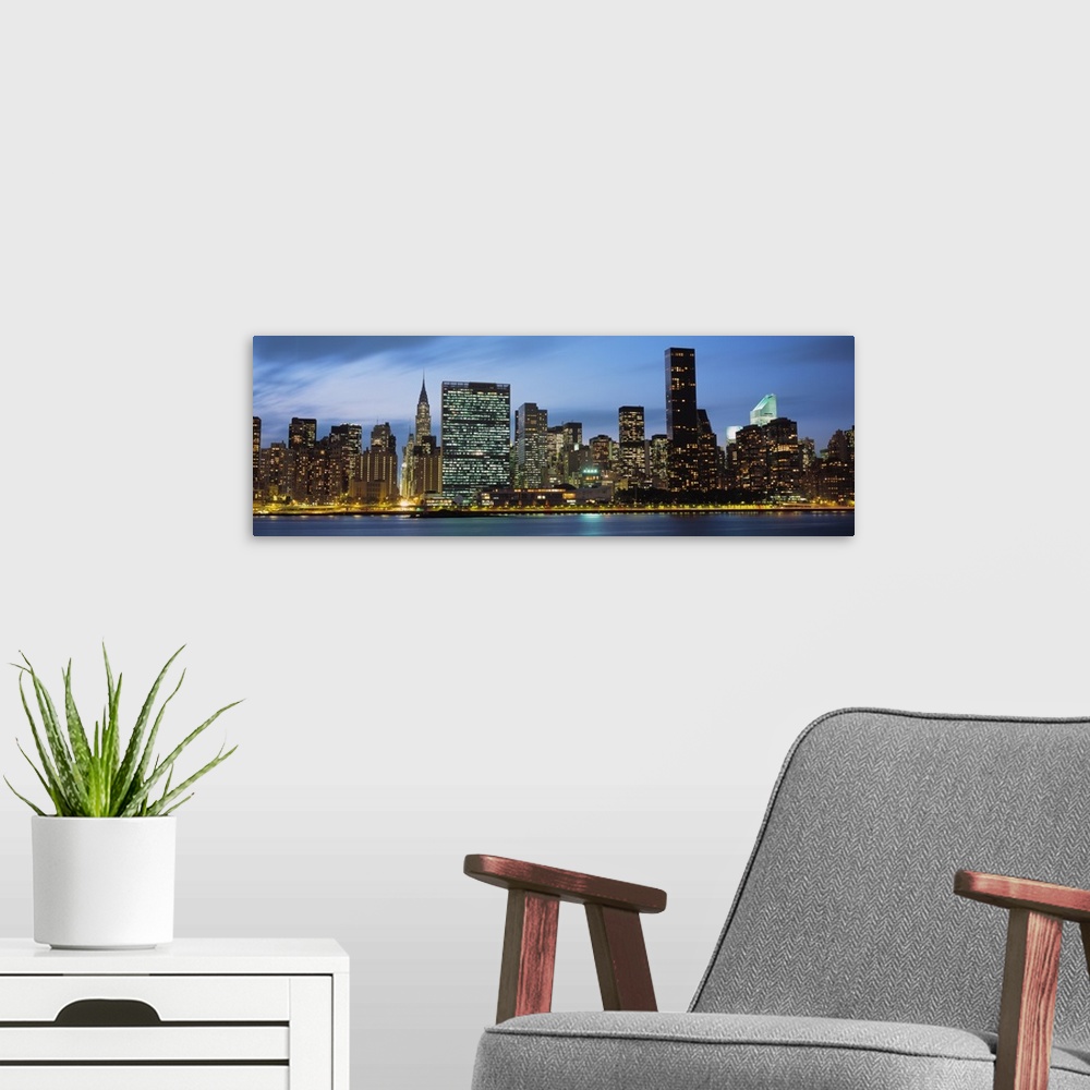 A modern room featuring Giant, panoramic photograph of the New York City skyline lit up at night.
