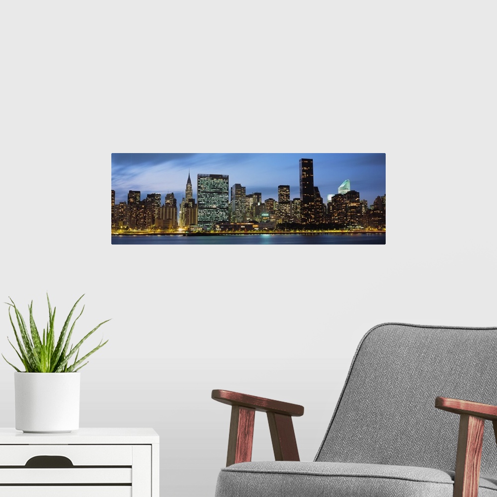 A modern room featuring Giant, panoramic photograph of the New York City skyline lit up at night.