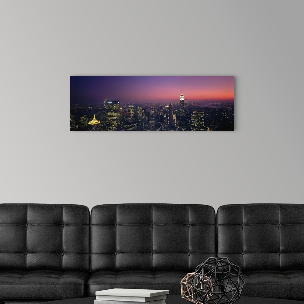 A modern room featuring Aerial view of New York City at late dusk with lit up office buildings, the Chrysler Building, an...