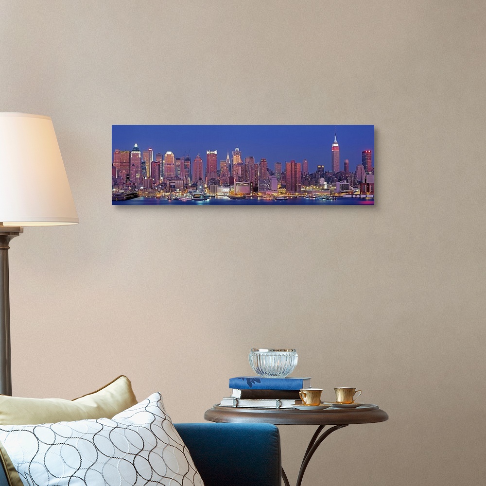 A traditional room featuring Wide angle photograph of the West side of the New York City skyline, lit up at night, against a d...