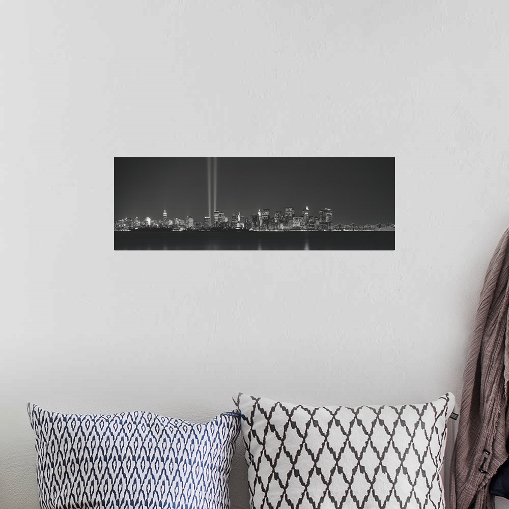 A bohemian room featuring Panoramic vista of the New York City skyline in the evening, with beams of light from the World T...