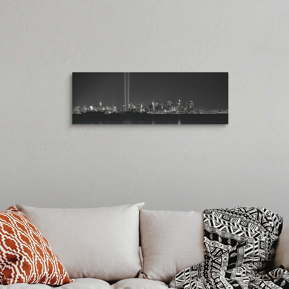 A bohemian room featuring Panoramic vista of the New York City skyline in the evening, with beams of light from the World T...