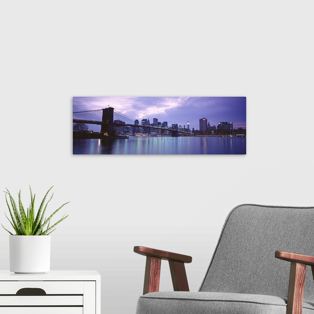A modern room featuring Large, panoramic photograph of the New York skyline, lit up at night, the Brooklyn Bridge in the ...