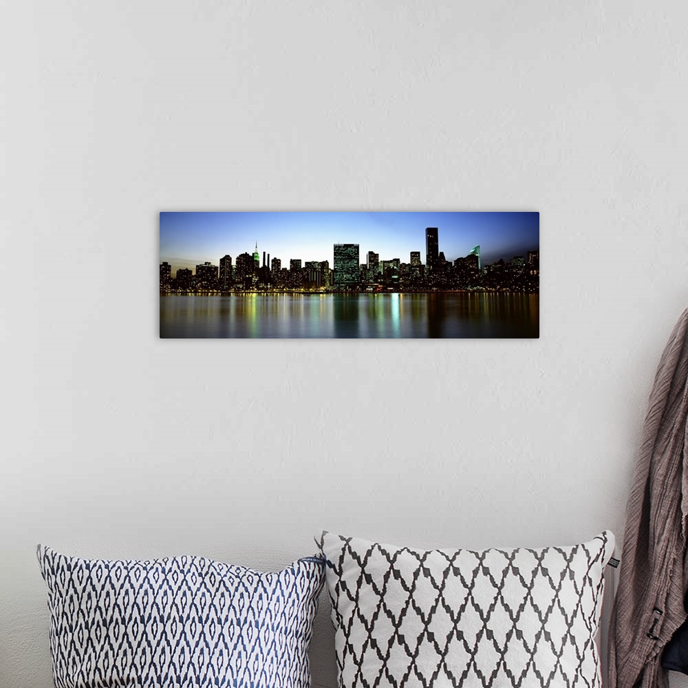 A bohemian room featuring Panoramic photograph of the New York City skyline, lit at dusk and reflecting in the waters in th...