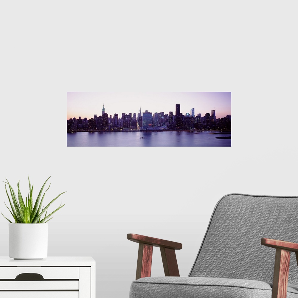 A modern room featuring Panoramic wall docor of the New York City cityscape along a waterfront at sunset.