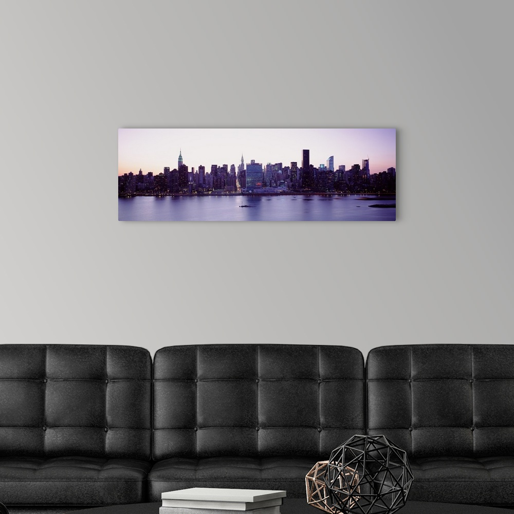 A modern room featuring Panoramic wall docor of the New York City cityscape along a waterfront at sunset.