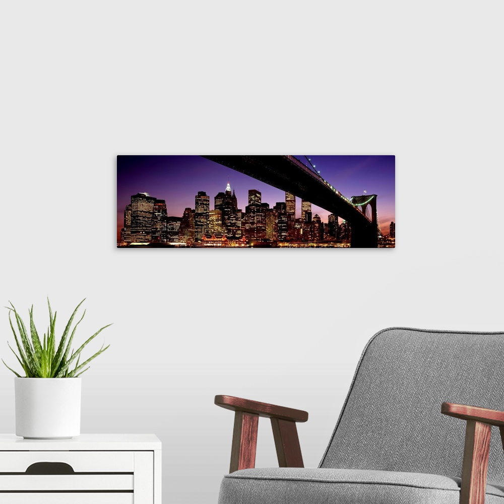 A modern room featuring The view of the Manhattan skyline taken from under the Brooklyn Bridge at night.