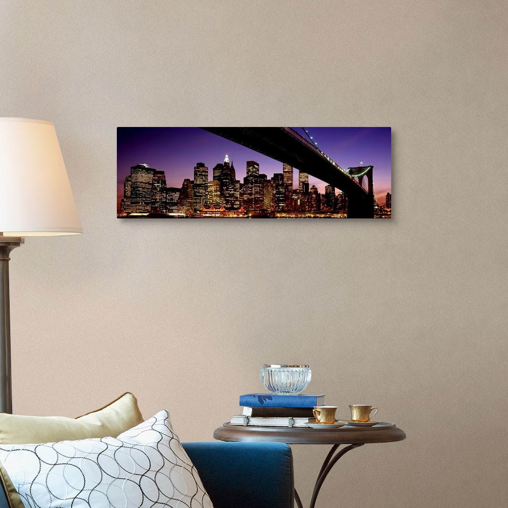 A traditional room featuring The view of the Manhattan skyline taken from under the Brooklyn Bridge at night.
