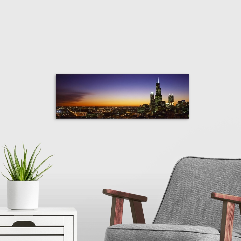 A modern room featuring Landscape photograph on a large wall hanging of the bright lights of the Chicago skyline at night...