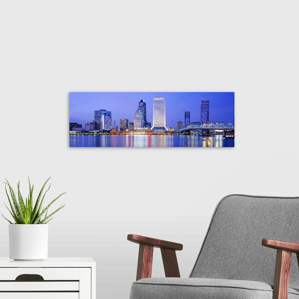 A modern room featuring This large panoramic photograph is of the Jacksonville skyline with it's buildings lit up at nigh...