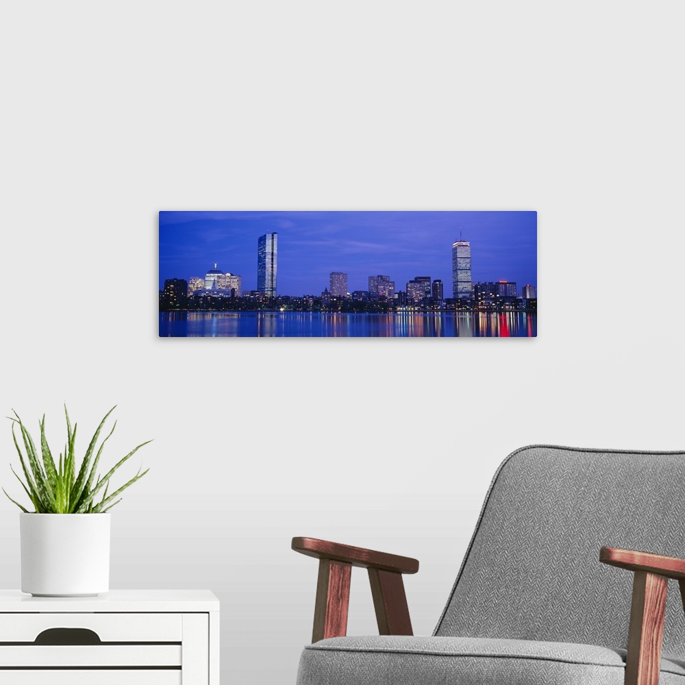 A modern room featuring Panoramic night skyline with building lights reflecting onto the waterfront.