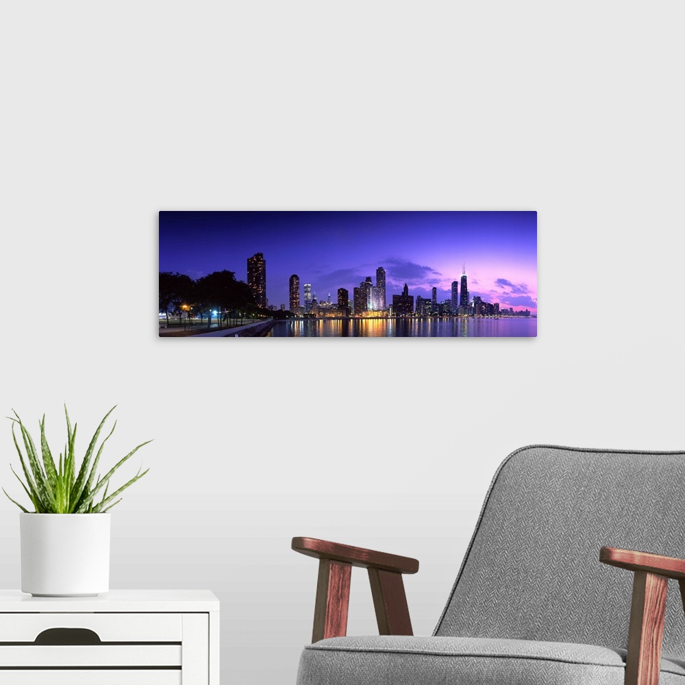 A modern room featuring A panoramic of the Chicago cityscape lit up at dusk and reflecting on Lake Michigan.