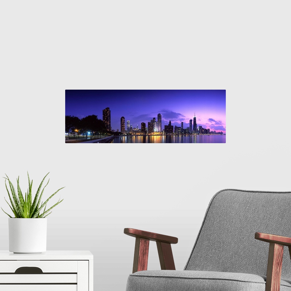 A modern room featuring A panoramic of the Chicago cityscape lit up at dusk and reflecting on Lake Michigan.