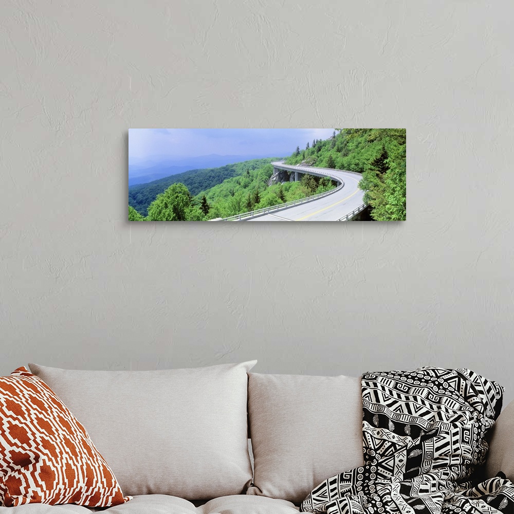 A bohemian room featuring Panoramic photograph of road winding through tree covered mountains.