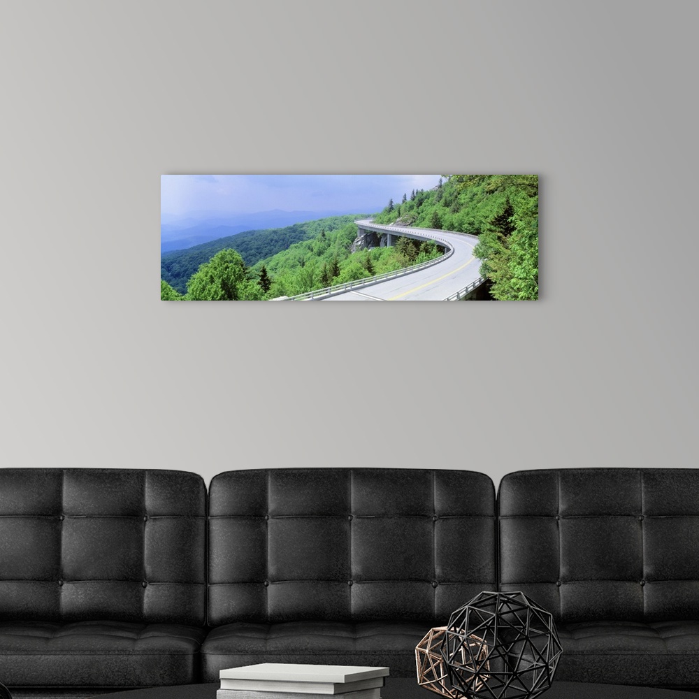 A modern room featuring Panoramic photograph of road winding through tree covered mountains.