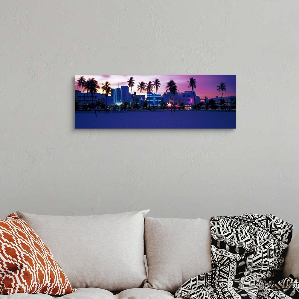 A bohemian room featuring Oversized, landscape photograph of palm trees along Miami Beach, the lit buildings along Ocean Dr...