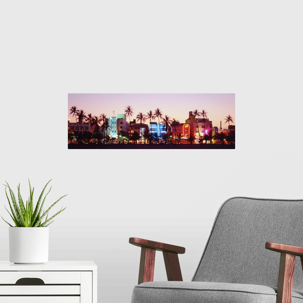 A modern room featuring A panoramic photograph of a sunset featuring Miami's Ocean Drive and the neon lights of the Art D...