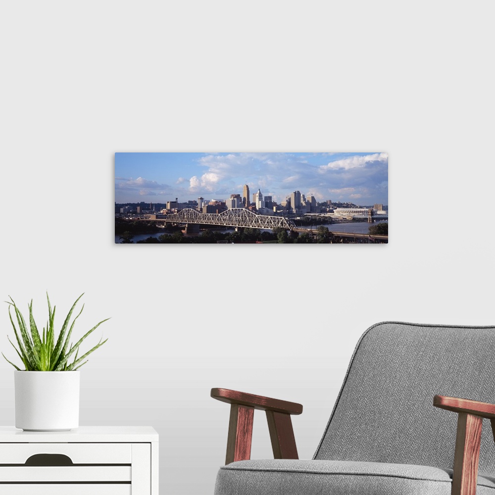 A modern room featuring Wide angle photograph taken of the Cincinnati skyline from a distance with a clear view of the br...
