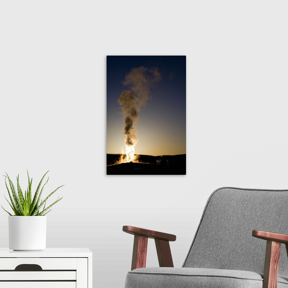 A modern room featuring Portrait photograph on a big wall hanging of steam rising into the air as Old Faithful erupts as ...