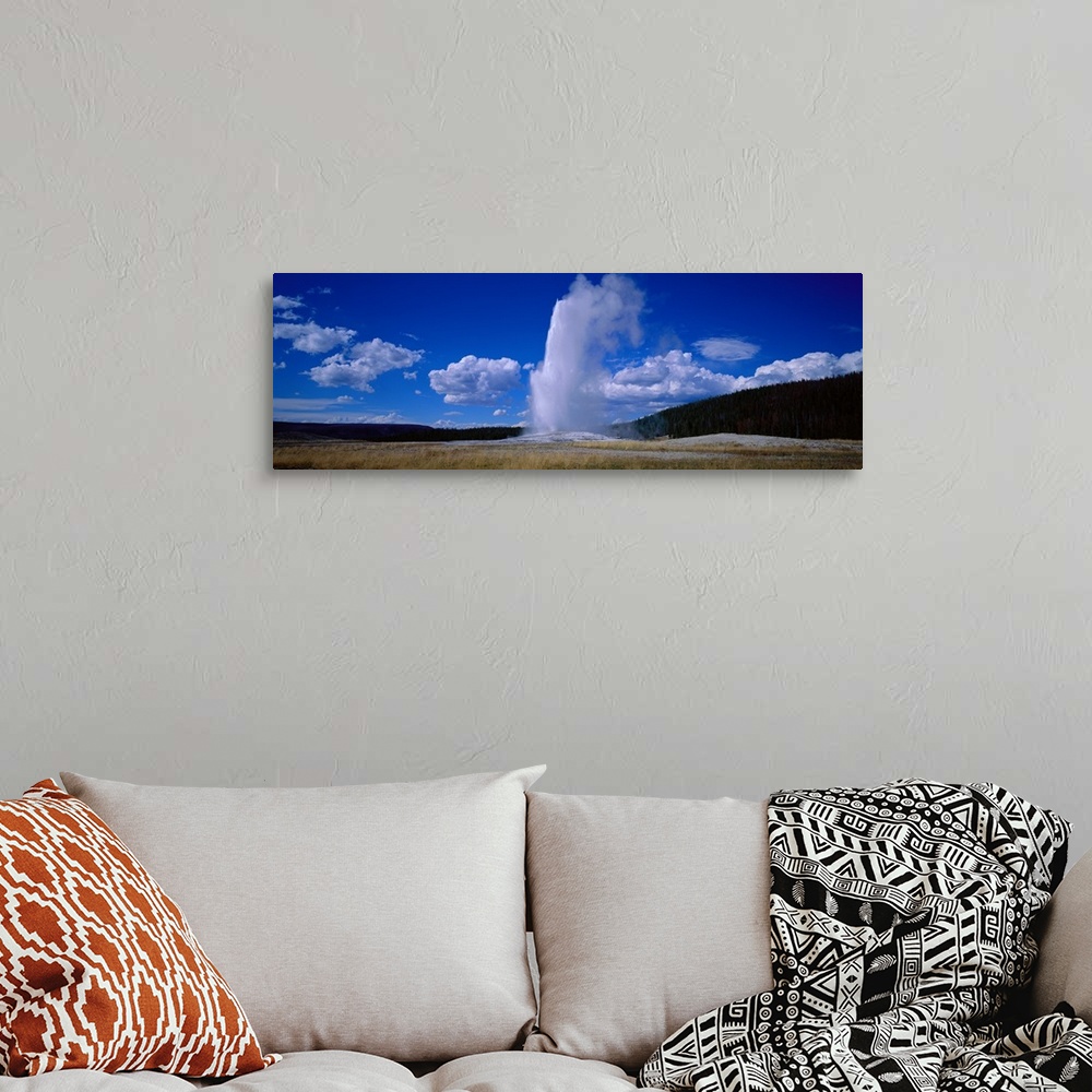 A bohemian room featuring Panoramic photo of a geyser shooting out steam at Yellowstone.